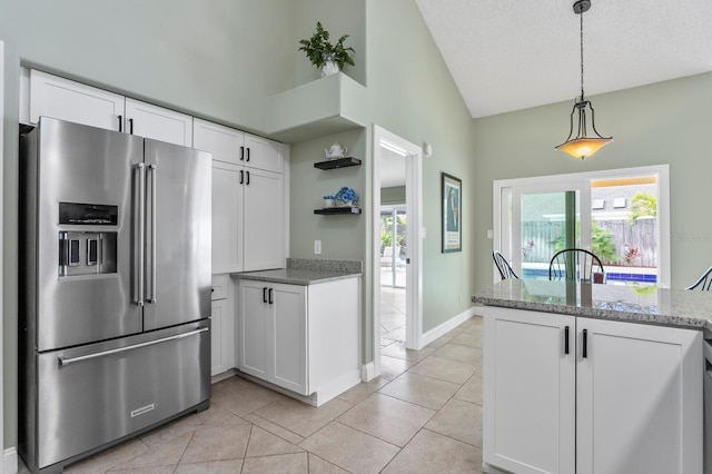 kitchen featuring light tile patterned flooring, light stone counters, decorative light fixtures, high quality fridge, and white cabinets