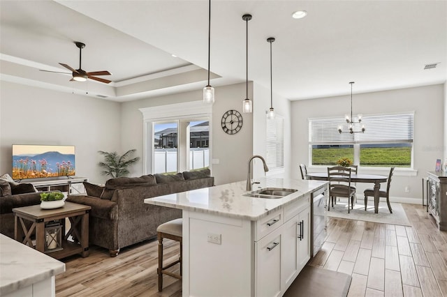 kitchen with dishwasher, sink, white cabinets, a raised ceiling, and light stone countertops