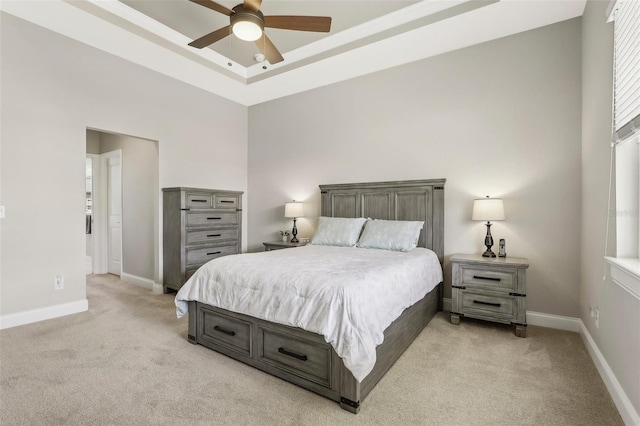 carpeted bedroom featuring a high ceiling, ceiling fan, and a tray ceiling