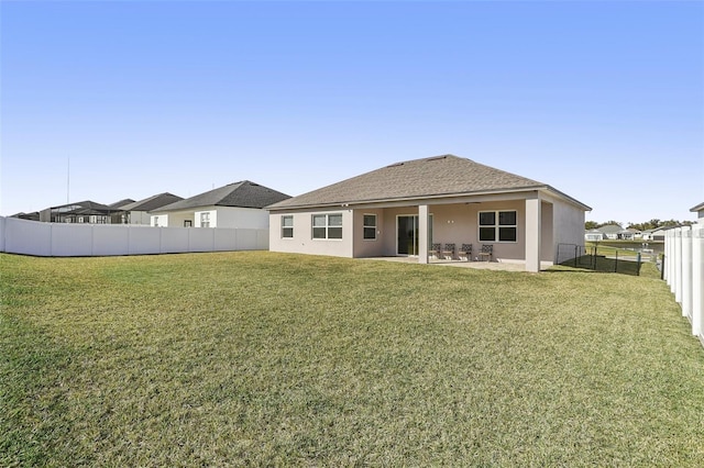 rear view of house featuring a yard and a patio