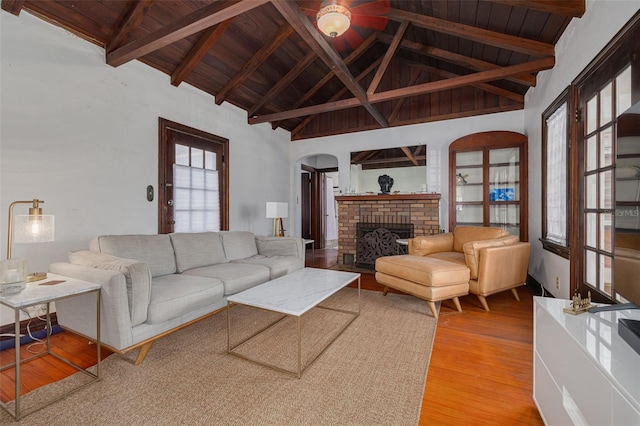 living room featuring a brick fireplace, wooden ceiling, beamed ceiling, and light wood-type flooring