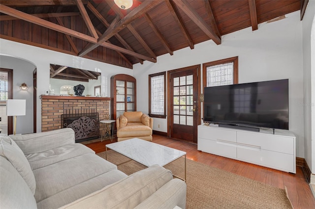 living room with beamed ceiling, hardwood / wood-style floors, a brick fireplace, and wooden ceiling