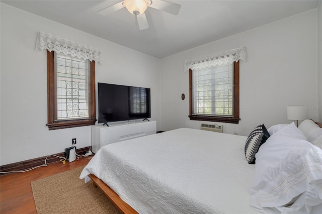 bedroom featuring wood-type flooring, an AC wall unit, and ceiling fan