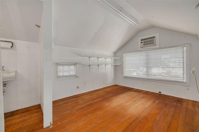 bonus room with lofted ceiling, sink, a wall mounted AC, and hardwood / wood-style floors