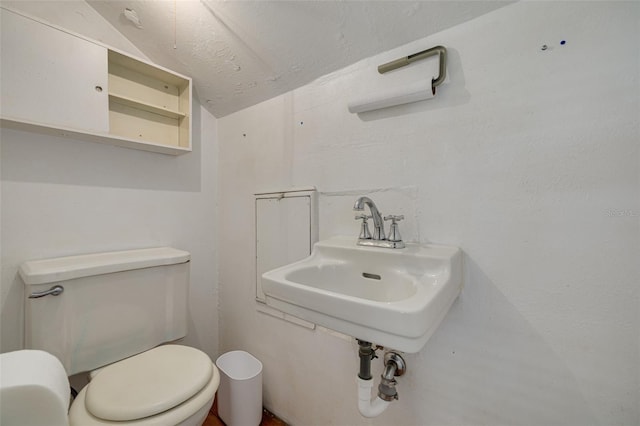 bathroom featuring sink, a textured ceiling, vaulted ceiling, and toilet