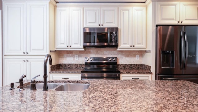 kitchen featuring light stone countertops, appliances with stainless steel finishes, sink, and backsplash