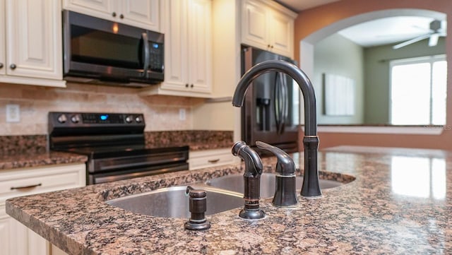 kitchen with sink, dark stone countertops, electric range, and ceiling fan