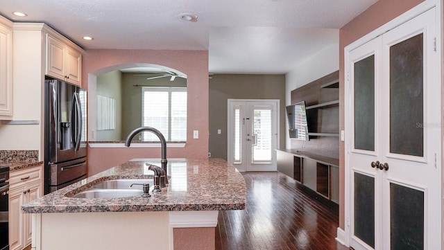 kitchen featuring french doors, dark stone counters, stainless steel fridge, and sink