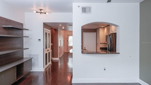 kitchen featuring dark hardwood / wood-style flooring, stainless steel fridge with ice dispenser, and dark stone counters