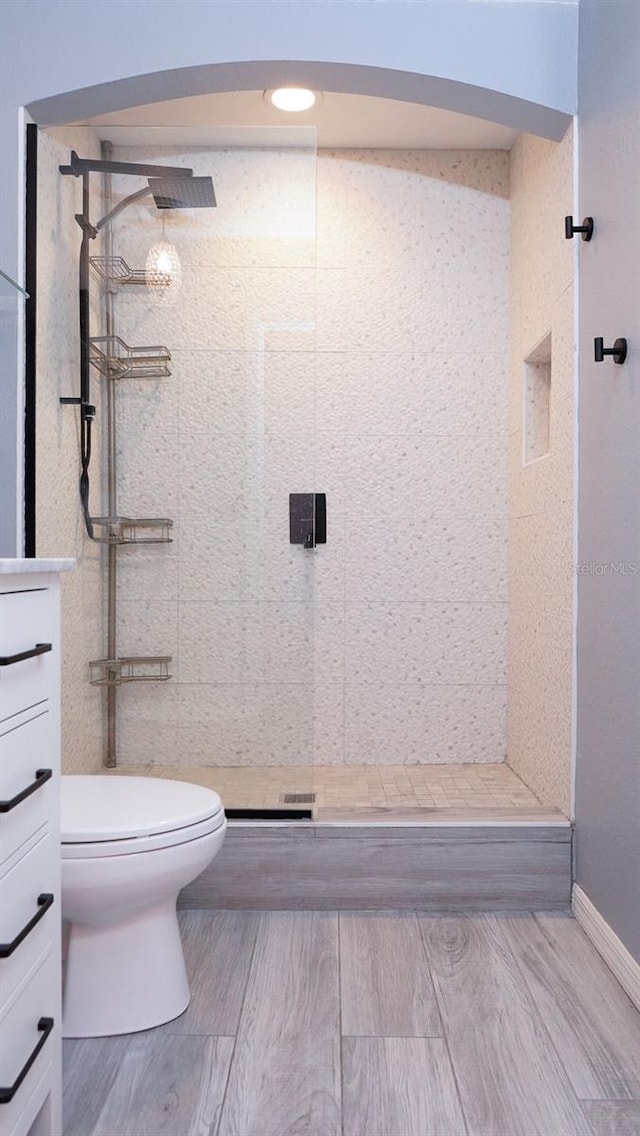 bathroom featuring a tile shower, vanity, and toilet