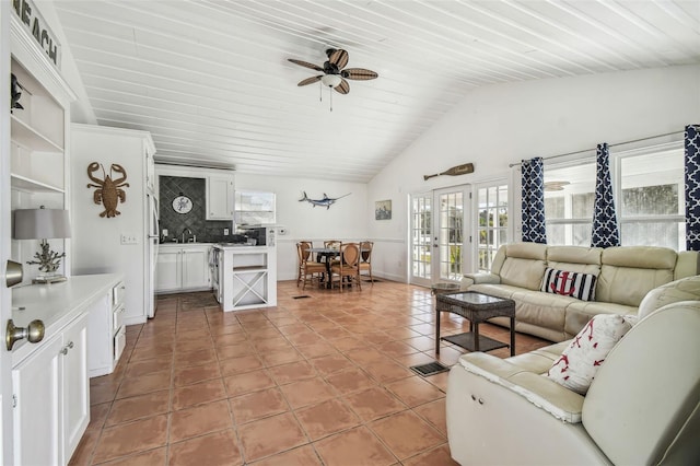 living room with light tile patterned floors, a wealth of natural light, ceiling fan, and vaulted ceiling