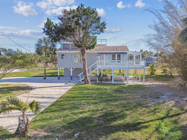 view of front of property featuring a garage, a front lawn, and a sunroom