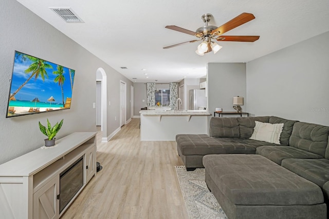 living room with ceiling fan, sink, and light hardwood / wood-style floors