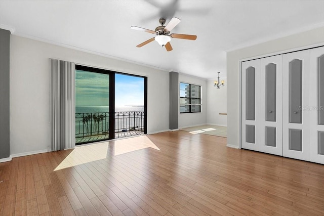 empty room featuring crown molding, ceiling fan with notable chandelier, and light wood-type flooring