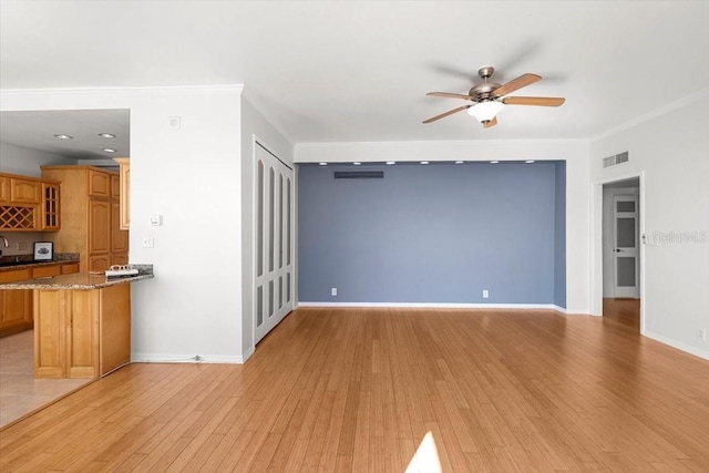 unfurnished living room with ceiling fan, ornamental molding, and light hardwood / wood-style flooring