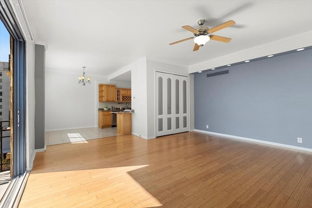 unfurnished living room featuring ceiling fan with notable chandelier and light hardwood / wood-style flooring