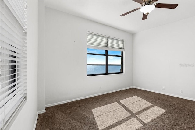 unfurnished room with ceiling fan and dark carpet