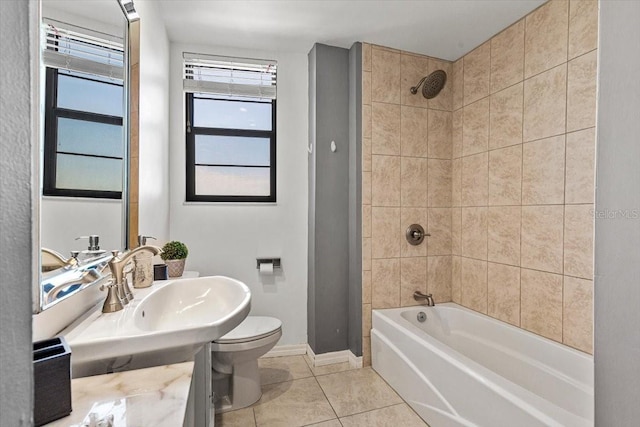 bathroom featuring tiled shower / bath, tile patterned floors, and toilet