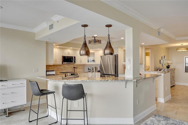 kitchen featuring hanging light fixtures, ornamental molding, stainless steel appliances, and a breakfast bar