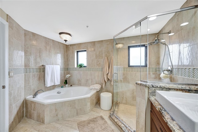 bathroom with shower with separate bathtub, tile walls, and vanity