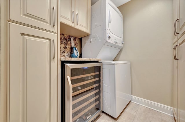 washroom with wine cooler, stacked washer and dryer, and cabinets