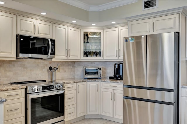 kitchen featuring light stone counters, appliances with stainless steel finishes, crown molding, and backsplash