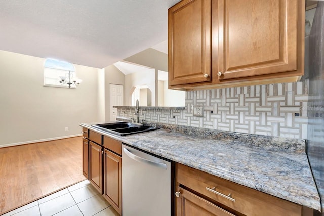 kitchen with light tile patterned flooring, sink, dishwasher, light stone countertops, and decorative backsplash