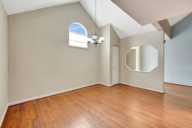 unfurnished room with vaulted ceiling, baseboards, wood finished floors, and an inviting chandelier