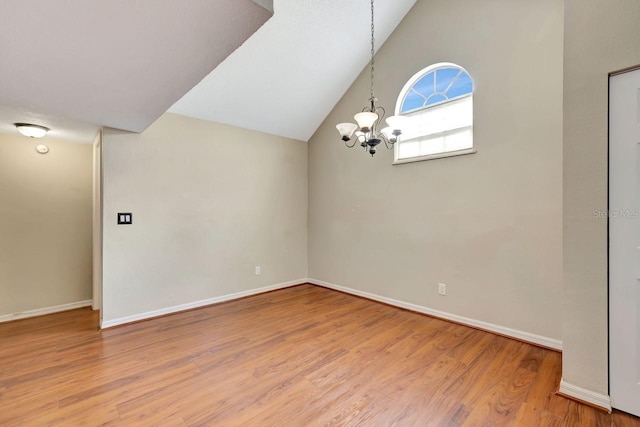 unfurnished room with a notable chandelier, baseboards, and wood finished floors