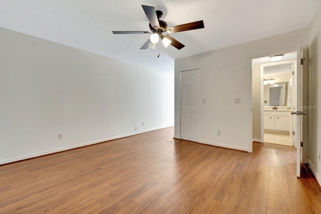 unfurnished bedroom with connected bathroom, sink, a textured ceiling, ceiling fan, and light hardwood / wood-style floors