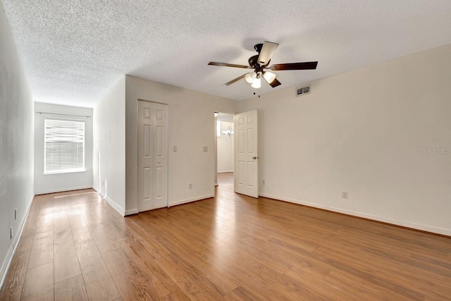 empty room with ceiling fan, light hardwood / wood-style floors, and a textured ceiling