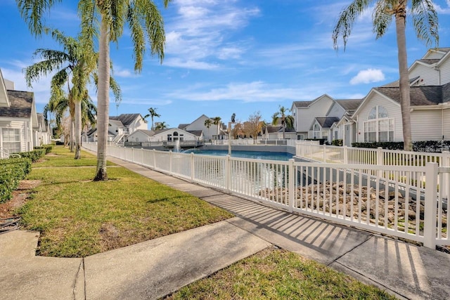 view of pool featuring a lawn, a residential view, fence, and a fenced in pool