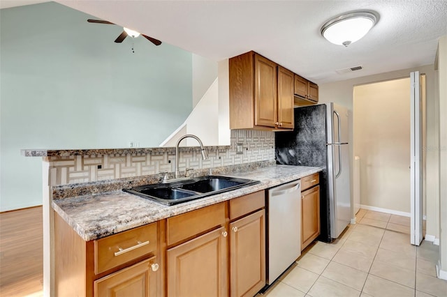 kitchen featuring sink, light stone counters, light tile patterned floors, stainless steel dishwasher, and decorative backsplash