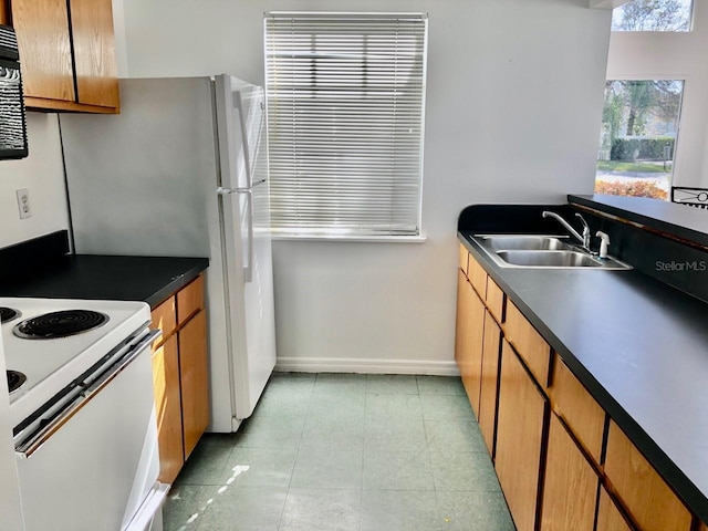 kitchen featuring dark countertops, electric stove, a sink, and light tile patterned floors