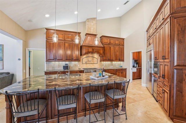 kitchen featuring a large island, decorative light fixtures, dark stone counters, and a kitchen bar