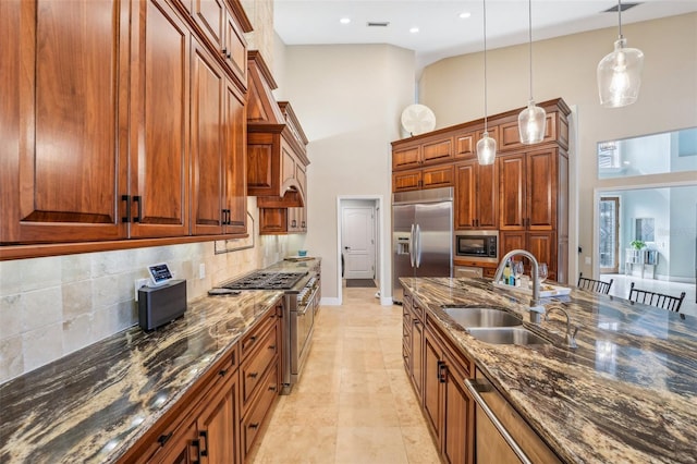 kitchen with pendant lighting, sink, backsplash, built in appliances, and dark stone counters