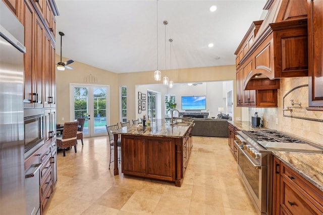 kitchen with a breakfast bar, double oven range, a center island with sink, decorative light fixtures, and french doors