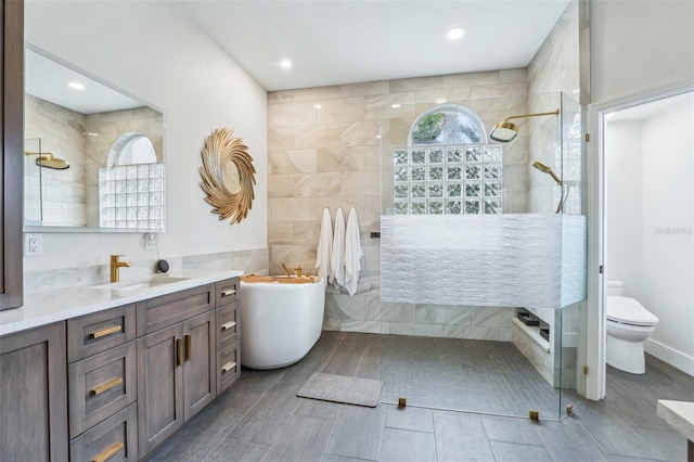 bathroom featuring a tile shower, vanity, toilet, and tile walls