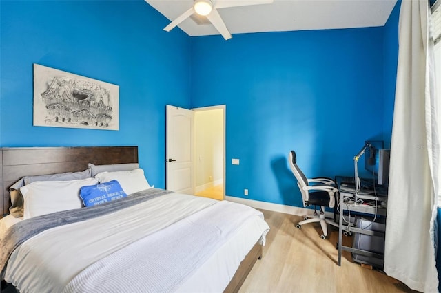 bedroom featuring ceiling fan, light hardwood / wood-style floors, and a high ceiling