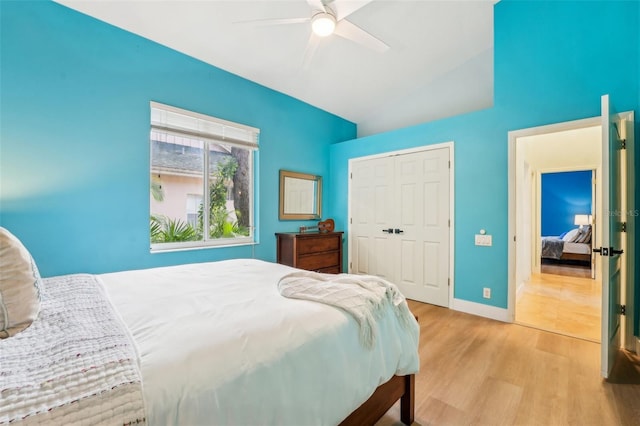 bedroom with baseboards, a ceiling fan, lofted ceiling, light wood-type flooring, and a closet