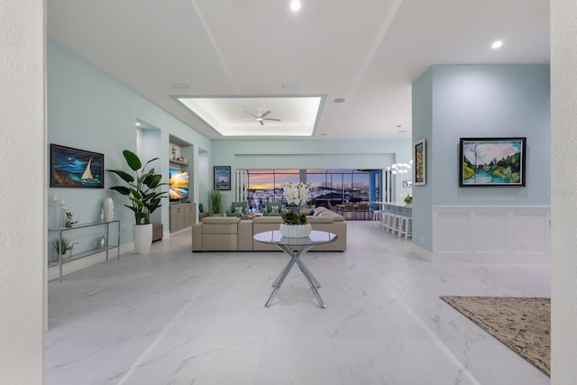 living room with a raised ceiling and ceiling fan