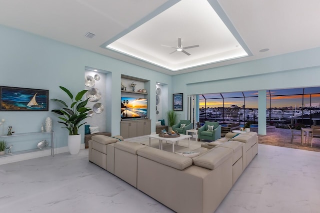 living room with ceiling fan and a tray ceiling