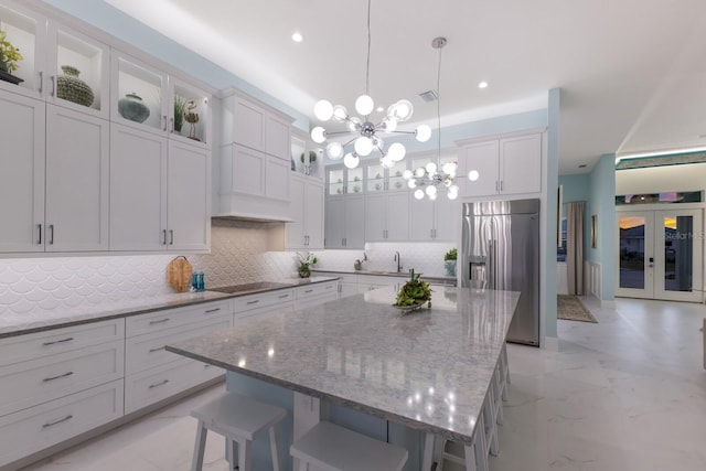 kitchen featuring hanging light fixtures, a center island, stainless steel built in refrigerator, a kitchen bar, and a chandelier