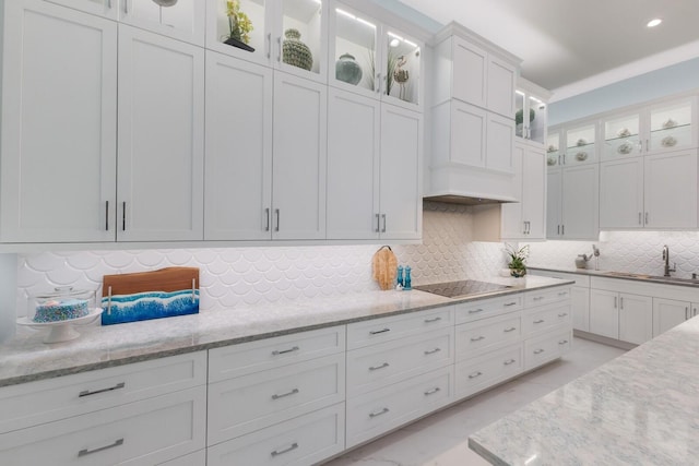 kitchen featuring white cabinetry, sink, light stone counters, and black electric cooktop