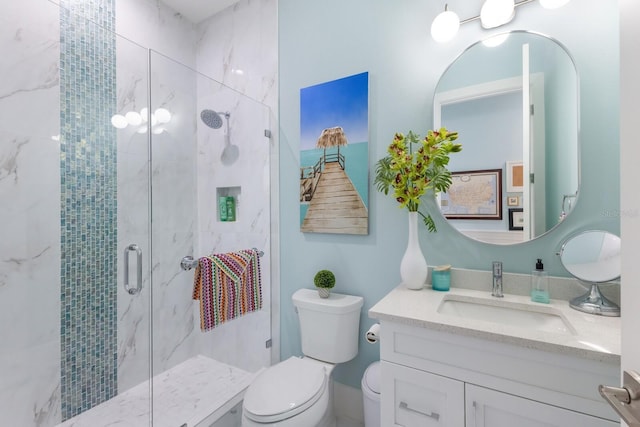 bathroom with toilet, vanity, and a shower with shower door