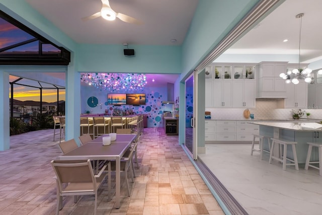 patio terrace at dusk featuring a bar, a lanai, and ceiling fan