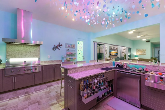 kitchen with light stone countertops, kitchen peninsula, extractor fan, and a breakfast bar area