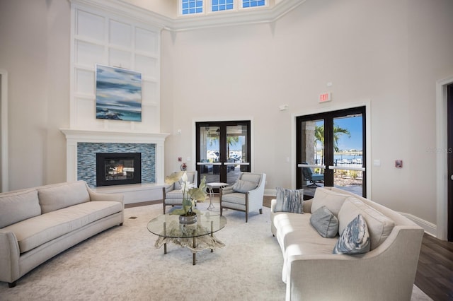 living room featuring hardwood / wood-style floors, a tile fireplace, french doors, and a high ceiling