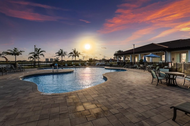 pool at dusk featuring a patio area