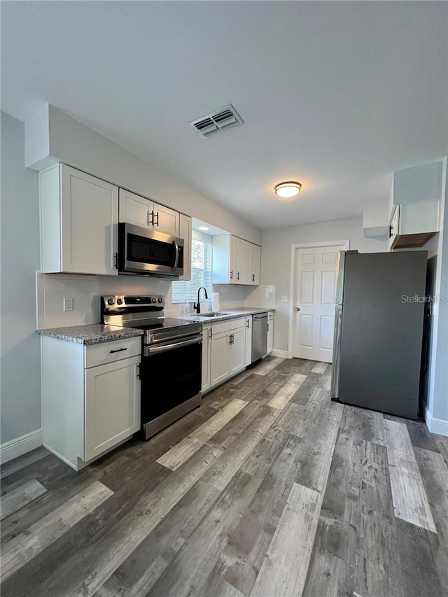 kitchen featuring sink, dark wood-type flooring, stainless steel appliances, and white cabinets